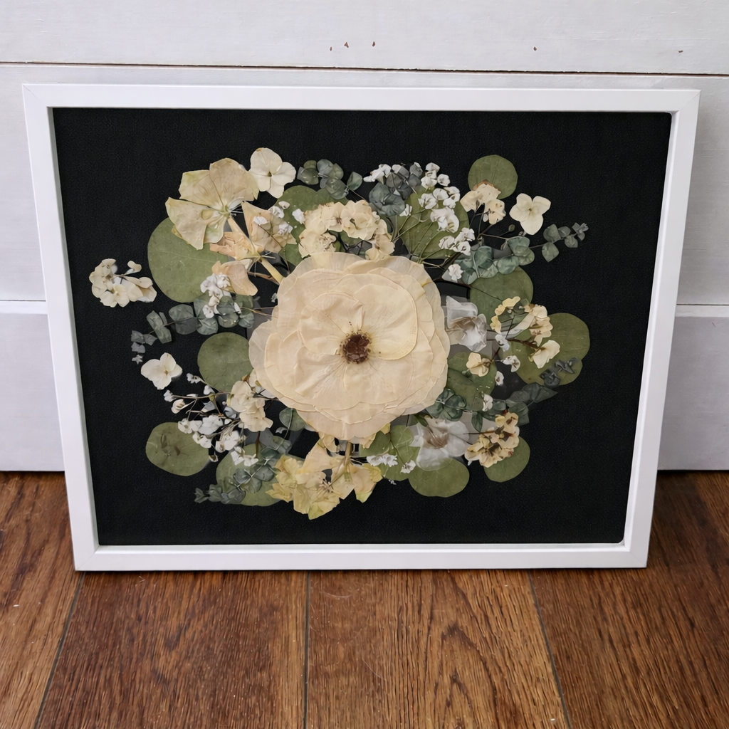 White framed pressed flowers on a black mat 